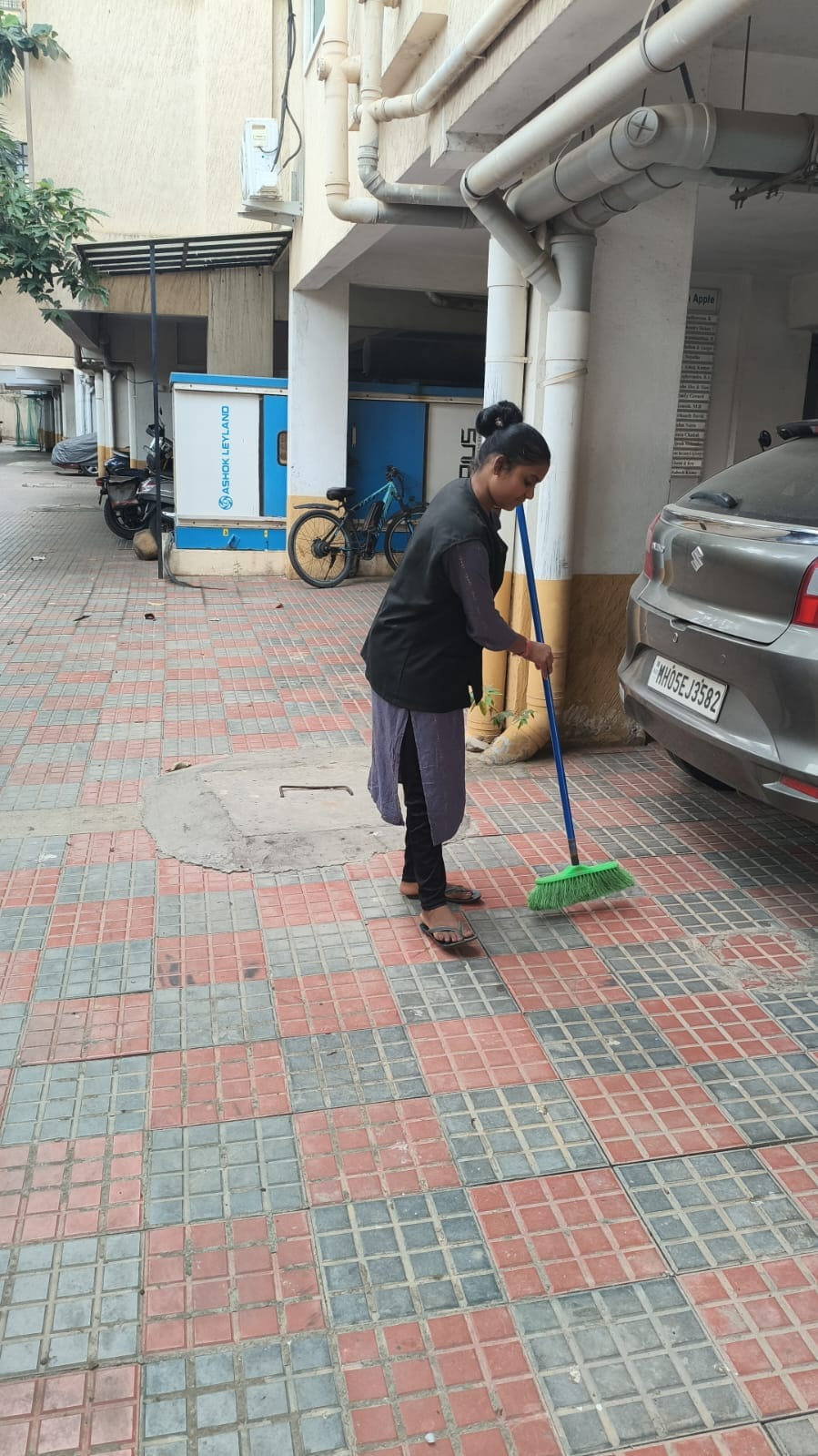 NV staff member sweeping a parking area beside a building