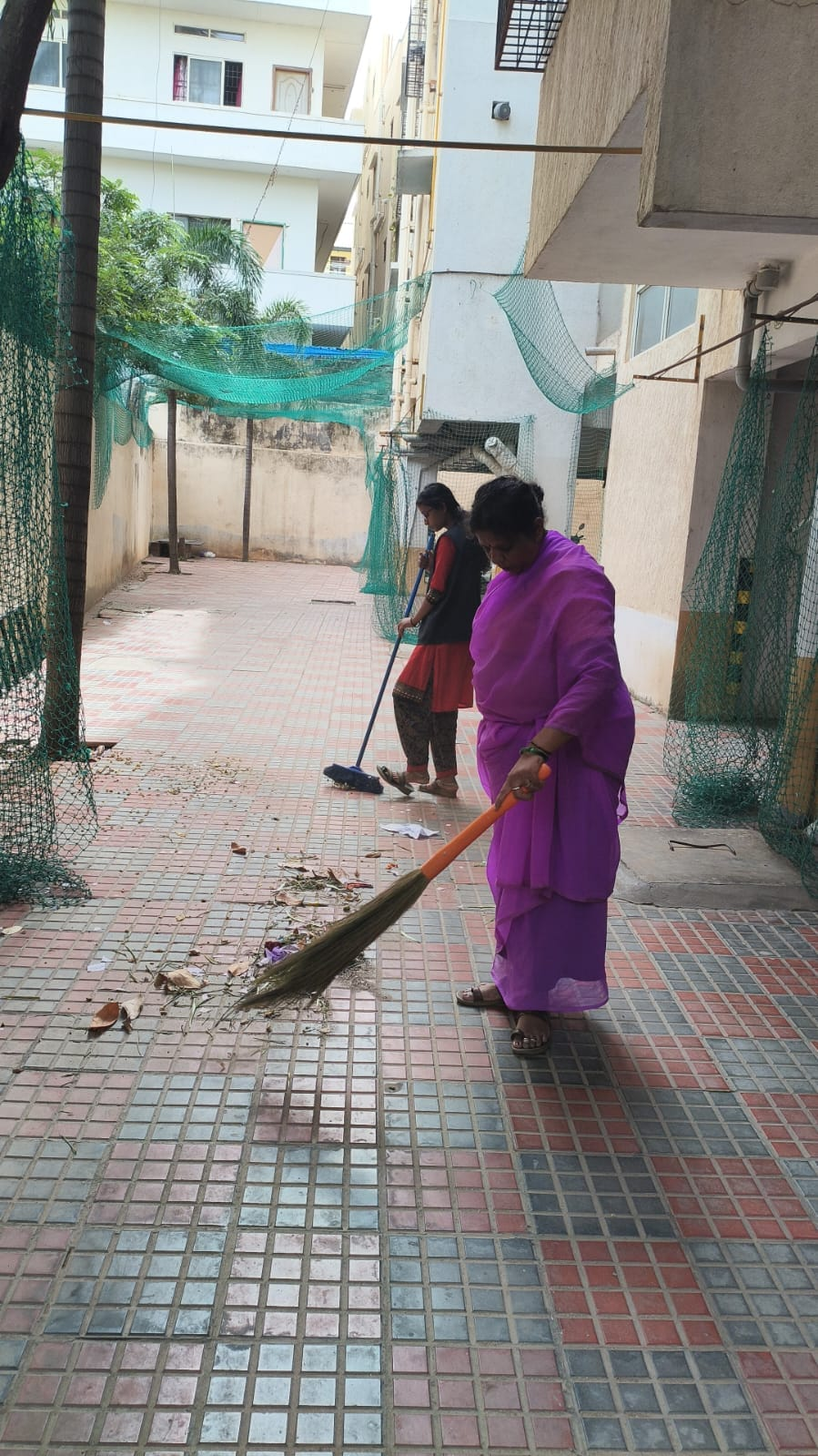 Two NV staff members cleaning an outdoor tiled area