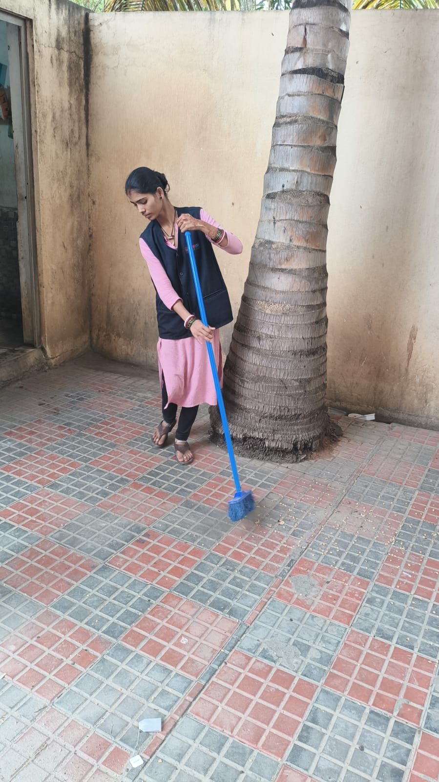 NV staff member sweeping a tiled outdoor courtyard