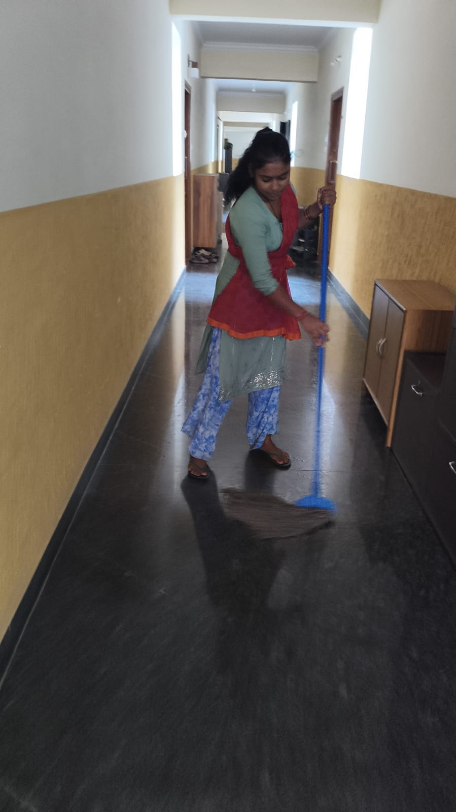 NV staff sweeping a polished indoor corridor